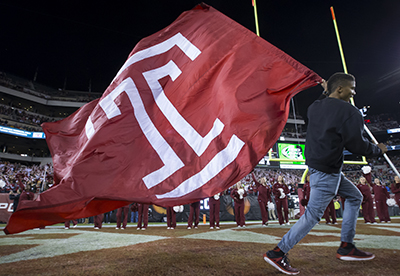 Student carrying Temple flag on football field