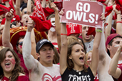 A group of students cheering at a Temple athletic event.