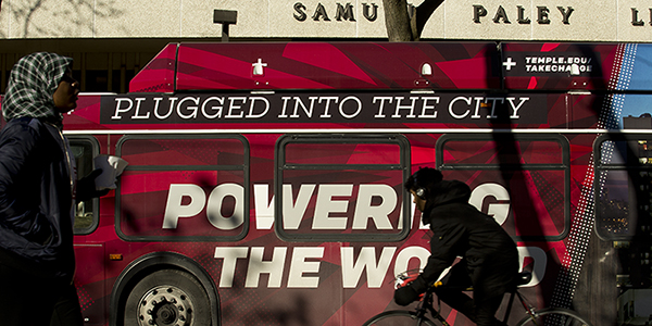 A Temple bus wrap that reads ‘plugged into the city, powering the world’ outside of Paley library. 
