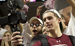  A student taking video of himself at a basketball game. 