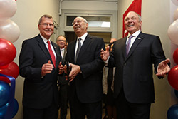 Three men smiling as they cut the ribbon at the veteran center.