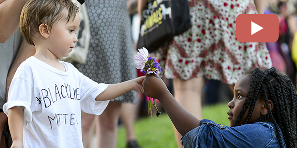 A young girl giving a young boy a flower at a Black Lives Matter protest.  