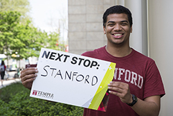 Chey Jones holding a sign that says “Stanford University.”