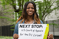 Jemie Fofana holding a sign that says “U.S. Court of Appeals for the D.C. Circuit”. 