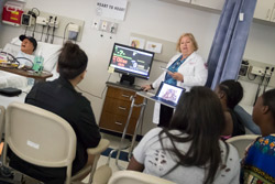 A nurse teaching a group of students in a hospital room