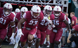 Temple football players running onto the field at a game