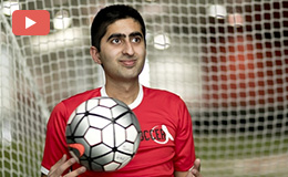 Haseeb Goheer holding a soccer ball in front of a goal net.  