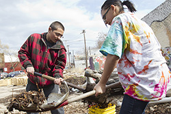 Two volunteers shoveling dirt into buckets. 
