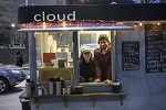 A man and a woman standing inside of a food truck.
