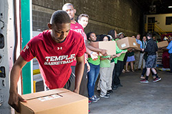 Temple men’s basketball players unloading a van at a food bank.