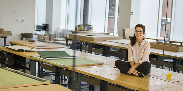Maryam Hallaj sitting on a studio table in the architecture building.