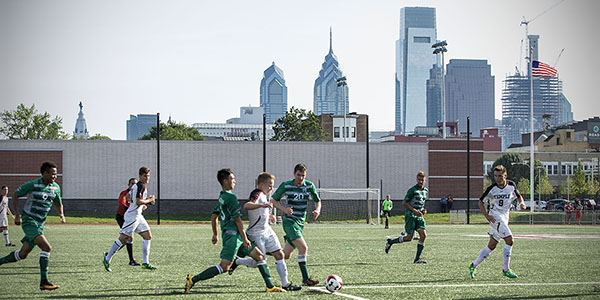 Temple men’s soccer team playing at the new sports complex with the Philadelphia skyline in the background.