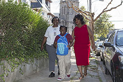 Two women and a young girl walking together through a residential neighborhood in North Philadelphia.