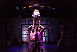 A woman doing a handstand supported by two men.