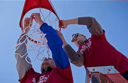 Two male student volunteers hanging a basketball net at Amos Recreation Center.