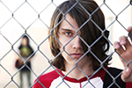 A boy from the documentary ‘The Bad Kids’ holding a chain link fence.