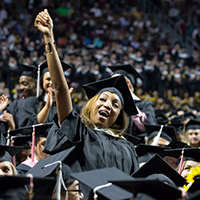 A woman in a cap and gown celebrating at Temple’s graduation ceremony.