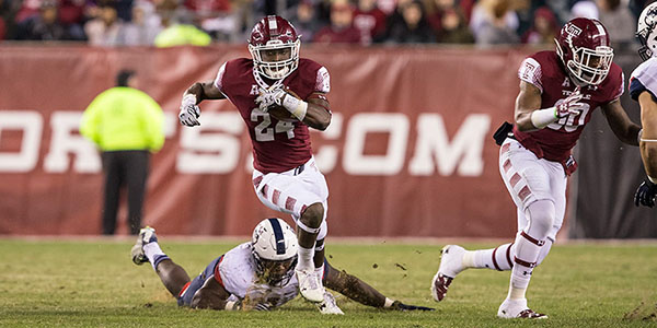 A Temple football player dodging a tackle in the game against UConn.