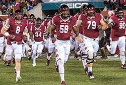Temple football players running on to the field.