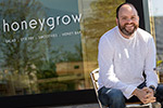 Justin Rosenberg sitting at a table outside of a honeygrow location.